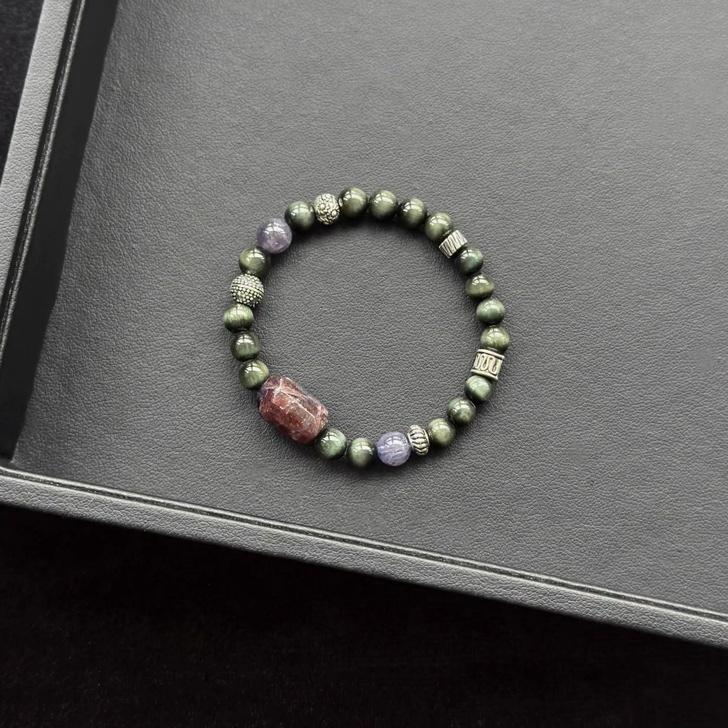 Bloodshot Iolite Sunstone & Actinolite Bracelet on a dark surface
