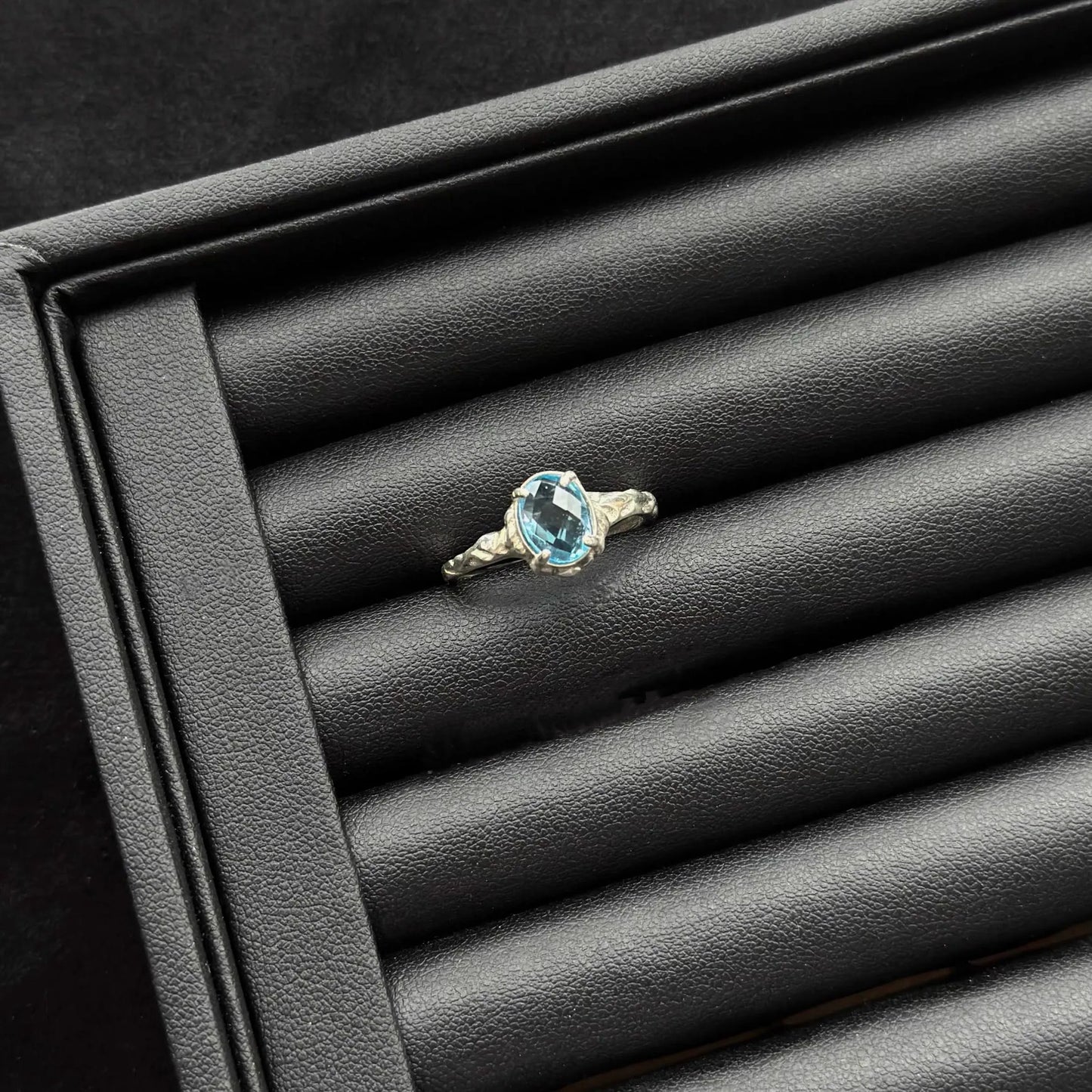 London Blue Topaz Sterling Silver Ring on a black textured surface