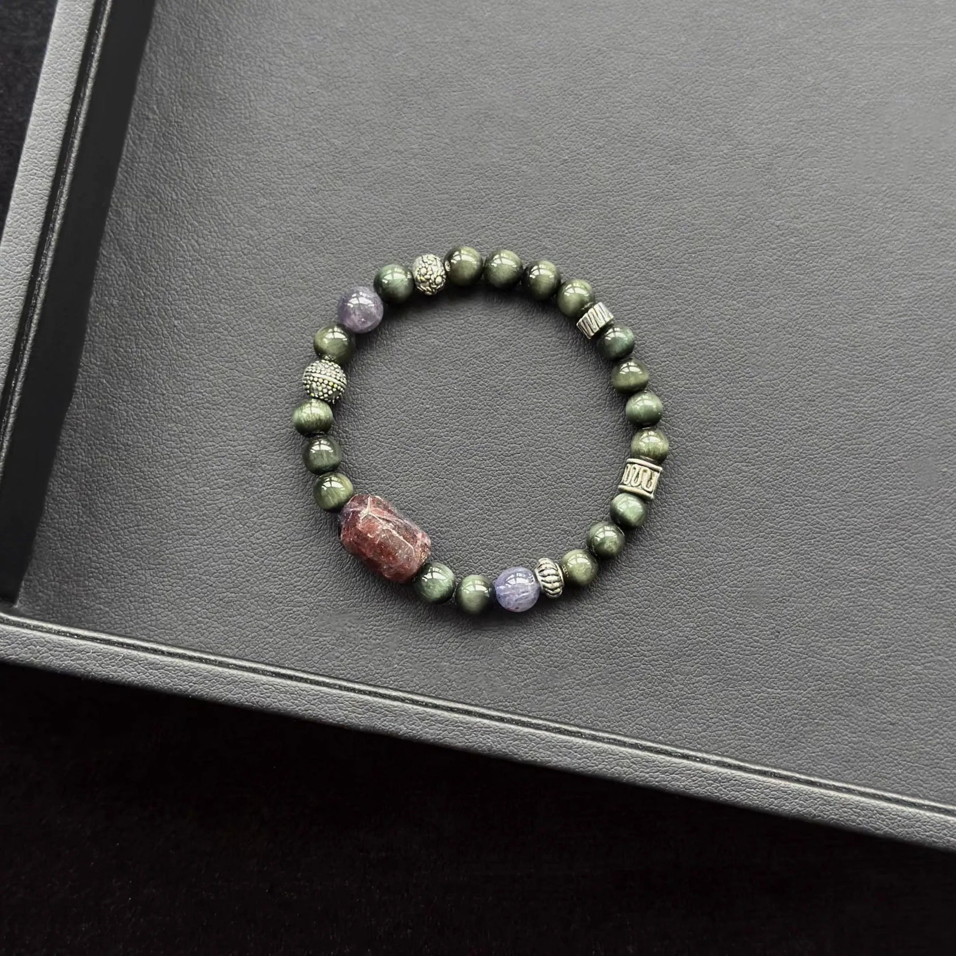 Bloodshot Iolite Sunstone & Actinolite Bracelet on a dark surface