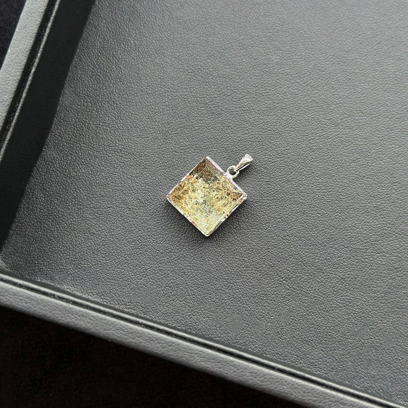Rectangle Four Season Azeztulite pendant with a textured surface on a dark surface