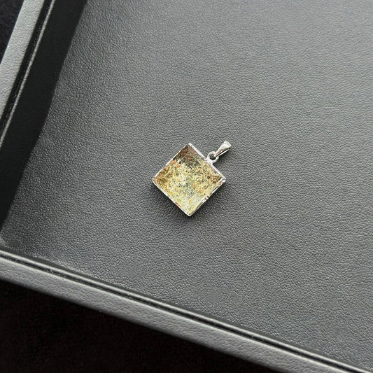 Rectangle Four Season Azeztulite pendant with a textured surface on a dark surface