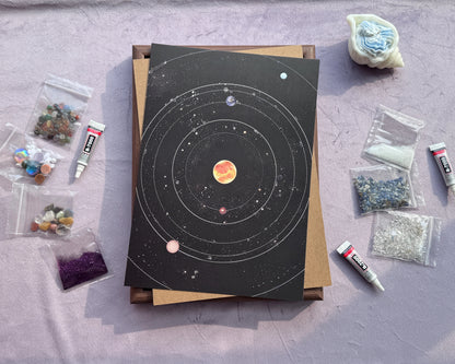 Workspace setup for the DIY Crystal Mosaic Art featuring the solar system canvas and craft supplies.