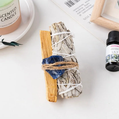 A spiritual room aesthetic smudge bundle featuring a raw blue sodalite stone bound with a white sage cleansing stick.
