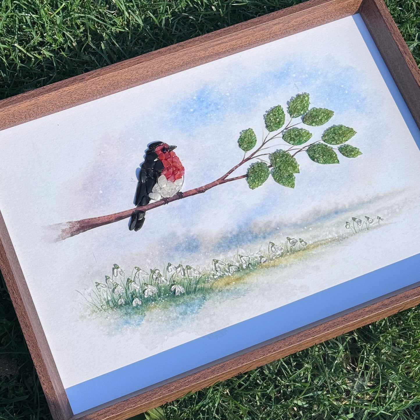 High-angle view of gemstone home accessories placed on grass, highlighting the wooden frame.