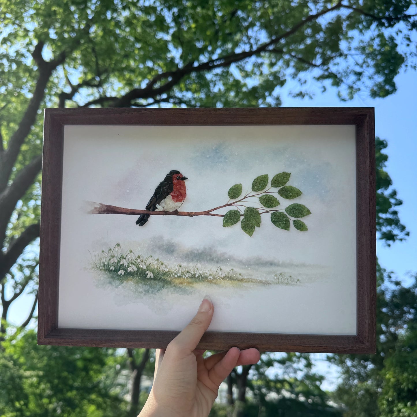 Hand holding the crystal bird frame to show size for home office decor.