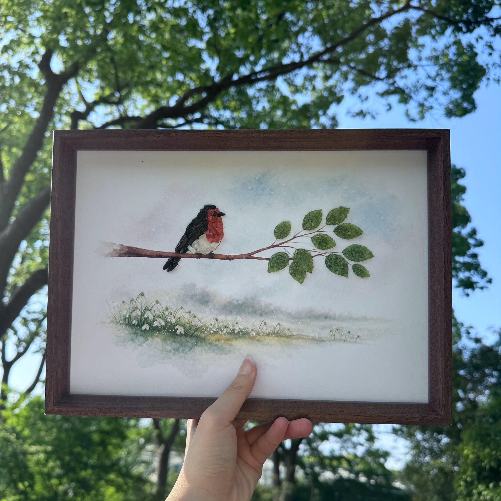 Hand holding the crystal bird frame to show size for home office decor.