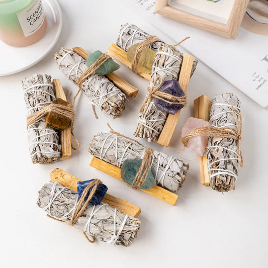 A collection of 7 raw crystal and white sage smudge bundles for spiritual cleansing and positive energy, featuring Rose Quartz, Clear Quartz, Amethyst, Citrine, and other healing stones.
