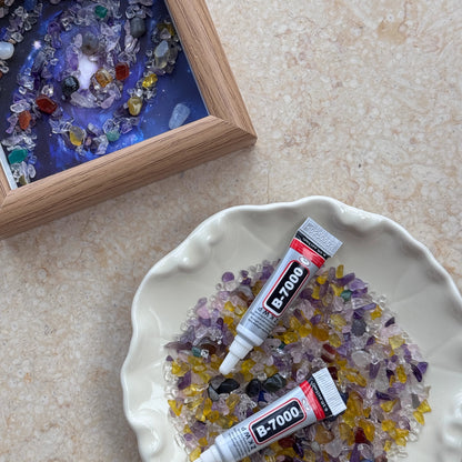Hands-on view of applying B-7000 glue to a crystal galaxy canvas for a creative calm activity.