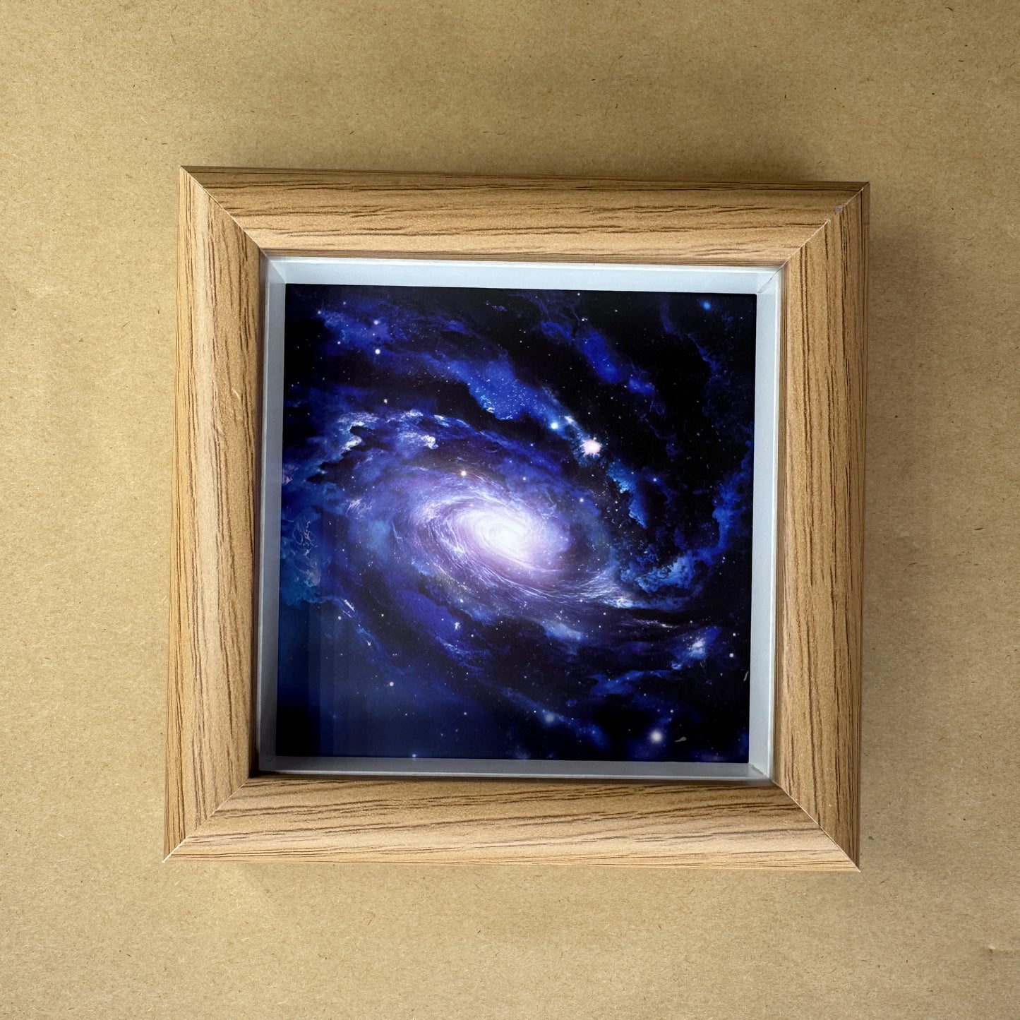 Close-up of the square deep-space nebula canvas print inside a light wood-grain frame.