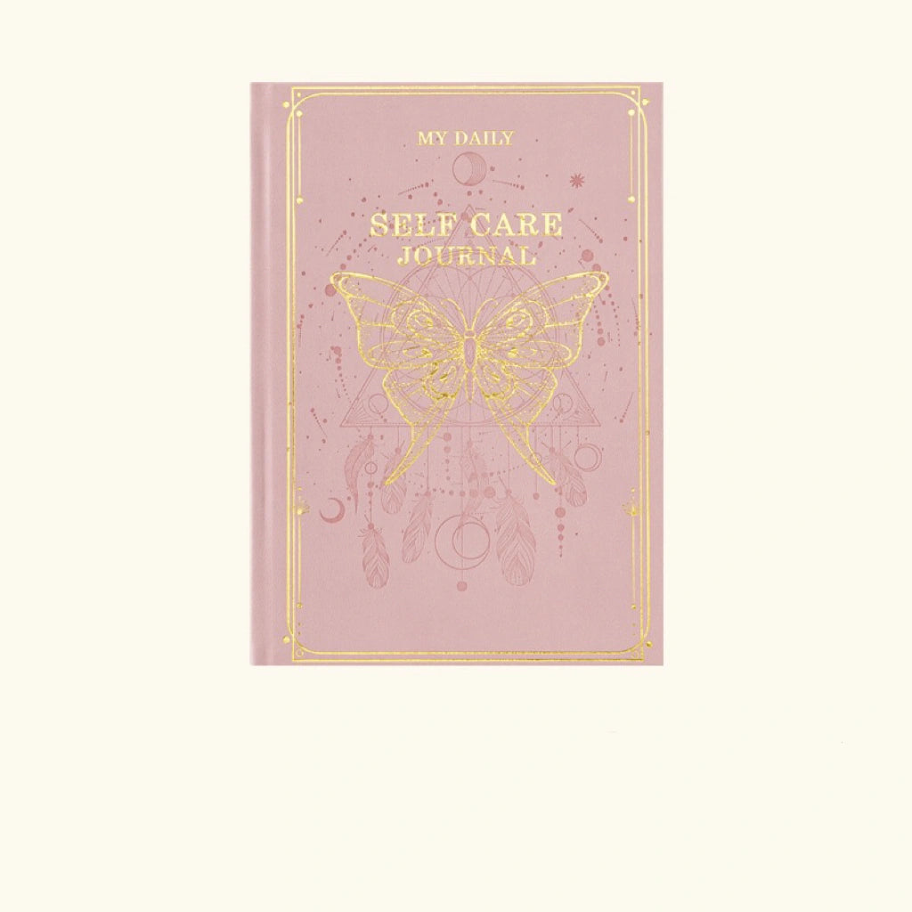 A pastel pink hardcover mindfulness journal featuring an intricate gold foil celestial sun design for positive energy decor.