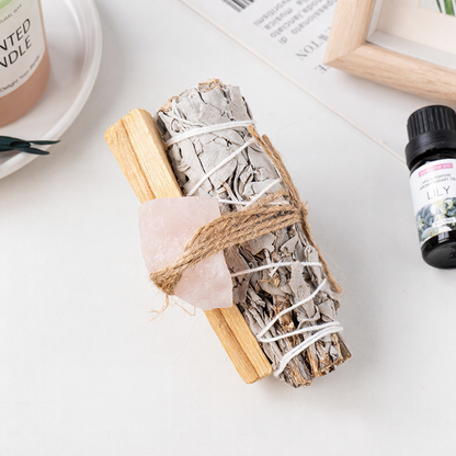 A spiritual cleansing bundle featuring a raw pink rose quartz crystal tied to a white sage smudge stick for love and positive energy decor.