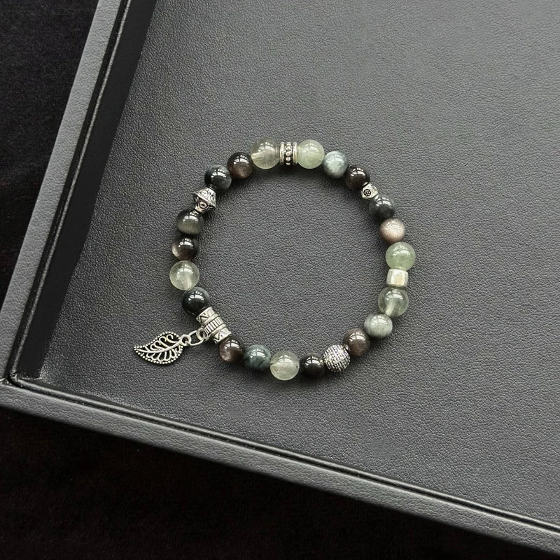 Healing crystal bracelet featuring Silver Obsidian, Hawk’s Eye, and Green Rutilated Quartz – supports grounding, protection, and mental clarity.