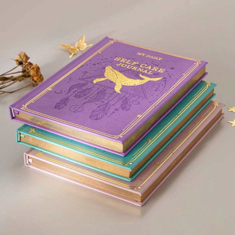 A stack of premium hardcover mindfulness notebooks with intricate golden sun and floral cosmic patterns, perfect for spiritual gifts.